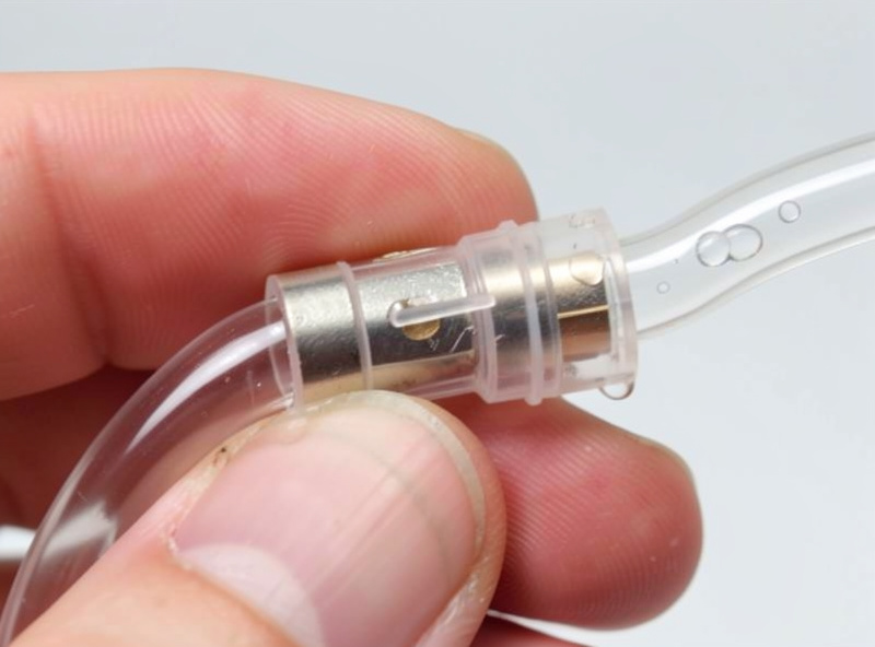 One-way check valve on clear aquarium airline tubing held in fingers with a water droplet inside the line