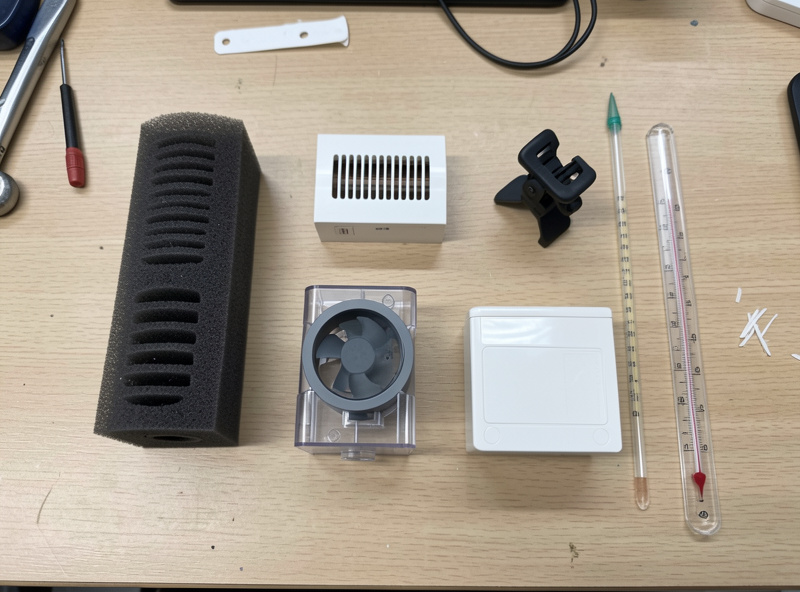 Separate aquarium components laid out on a workbench: sponge filter, heater, hang-on-back filter and light