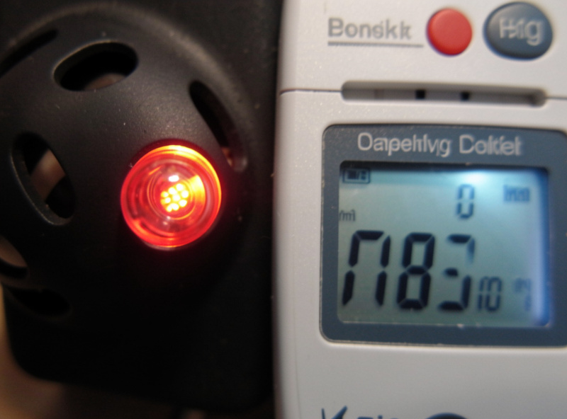 Macro close-up of an aquarium heater indicator light stuck on beside a digital thermometer reading a high temperature