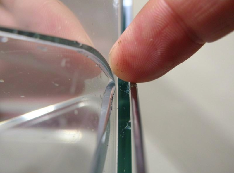 Fingertip running along the inside silicone bead of an aquarium corner checking for a peeled or gapped seal