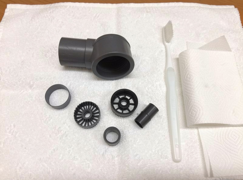 Small aquarium filter partially disassembled on a white towel with impeller and intake tube removed